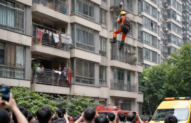 Para alcançar o idoso, Zhang amarrou uma mangueira de incêndio na cintura e desceu cuidadosamente a partir de uma janela localizada em um andar superior.